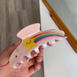 Detail of pink acetate hair claw with cute yellow star, rainbow and small rhinestones