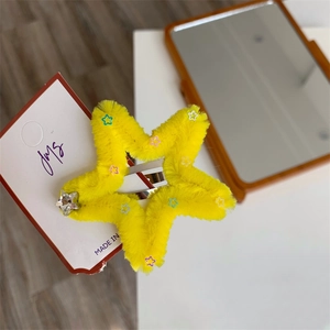 Dettaglio di un fermaglio per capelli a stella di peluche giallo con paillettes e strass