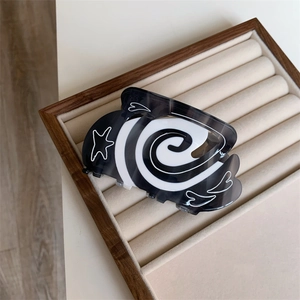 Detailed top view of the black and white acetate hair claw clip with star and heart patterns