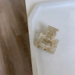 Detailed close-up of a handmade cream marble mini hair claw clip on a white tray