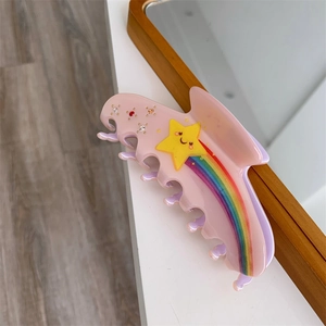 Detail view of pink acetate hair claw with smiling yellow star and rainbow rhinestone accents