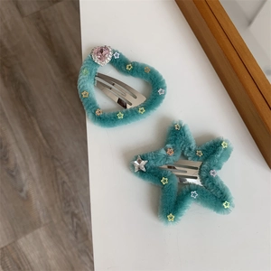 Dettaglio di fermagli per capelli in peluche blu a forma di cuore e stella con strass