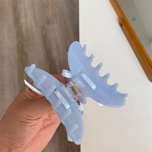 Gros plan sur une pince à cheveux bleue en forme de nœud avec ruban satiné et ressort doré