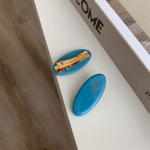 Close-up of blue acetate hair clips with gold France Handmade text and metal duckbill grip