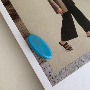 Close-up of blue acetate hair clip with gold France Handmade lettering on magazine page