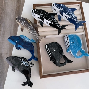 Vue détaillée des pinces à cheveux en acétate en forme de baleine et de requin