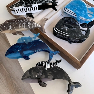 Vue détaillée de pinces à cheveux en acétate en forme de baleine et requin à motifs marbrés
