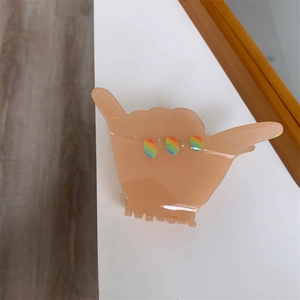 Macro detail of hand gesture hair claw clip with colorful oval accents on smooth resin