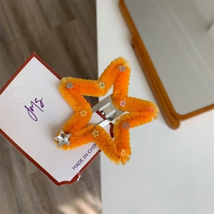 Dettaglio della molletta a stella arancione pelosa con paillettes e strass a stella