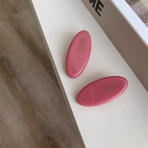 Detail of pink acetate oval hair clips with golden France Handmade lettering and glossy finish