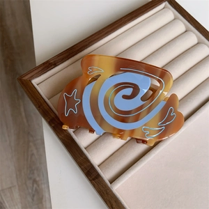 Detail of amber and blue star pattern hair claw clip on a velvet jewelry display tray