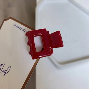 Detailed close-up of a red geometric mini hair claw clip with glossy finish