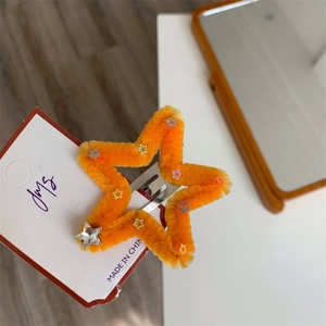 Dettaglio del fermaglio a stella con peluche arancione e strass argentato scintillante