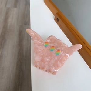 Close-up of pink marble acetate hair claw clip in a Shaka hand gesture shape
