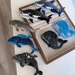 Détail des pinces à cheveux en acétate en forme de baleine bleue et de sardine marbrée