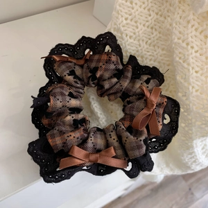 Detailed close-up of brown checkered scrunchie with lace trim and satin bows