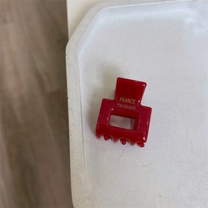 Detail of red acrylic hair claw clip with golden France Handmade text on marble