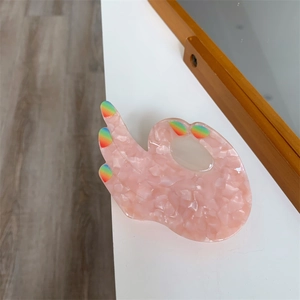 Close-up of pink marble pattern acetate hair claw in creative hand gesture shape