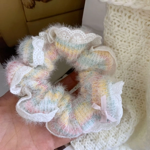 Gros plan d'un chouchou arc-en-ciel avec bordure en dentelle blanche et nœud rose
