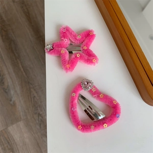 Dettaglio di fermagli per capelli rosa con forme a stella e cuore glitterate e strass
