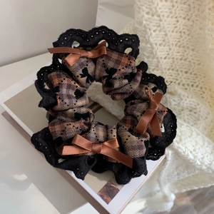 Detailed view of checkered hair scrunchie with lace trim and satin bow accents