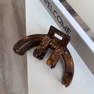 Close-up of tortoise shell pattern acetate hair claw with high-quality gold logo finish