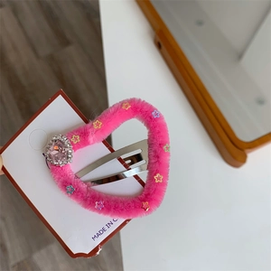 Dettaglio di un fermaglio per capelli in peluche rosa con stelle e strass scintillanti