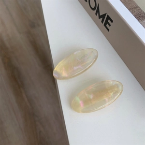 Macro shot of two cream pearlescent acetate hair clips with France Handmade engraving