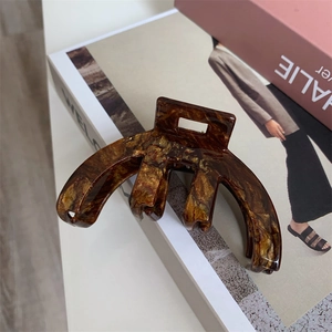 Close-up of a brown tortoise shell acetate hair claw clip on a decorative background