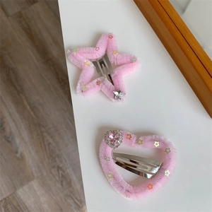 Vista dettagliata di fermagli per capelli in peluche rosa a forma di stella e cuore con strass