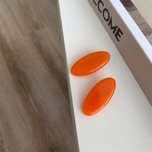 Close-up of orange handmade acetate hair clips on a minimalist lifestyle background
