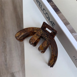 Detailed macro view of large dark brown acetate hair claw clip with tortoise shell pattern