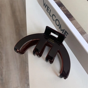 Detailed view of dark brown acetate hair claw with gold France Handmade logo engraving