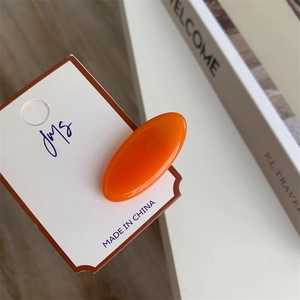 Detail showing smooth orange acetate duckbill hair clip with France Handmade lettering