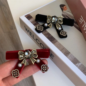 Detail of velvet bow hair clip with a large grey gemstone and golden rhinestone frame