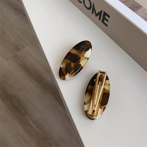 Detail of tortoise shell acetate hair clips with gold lettering and metal duckbill grip