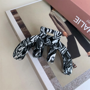 Detail of a large black and white marble acetate hair claw clip on a fashion magazine