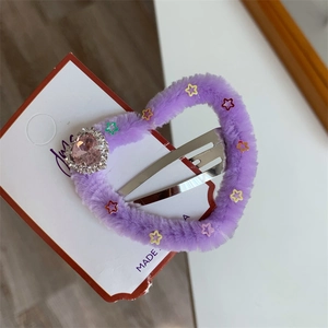 Dettaglio del fermaglio a cuore in peluche viola con gemma rosa e paillettes a stella