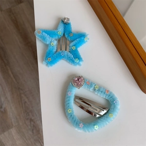 Dettaglio di fermagli blu in peluche con paillettes e gemma a forma di cuore