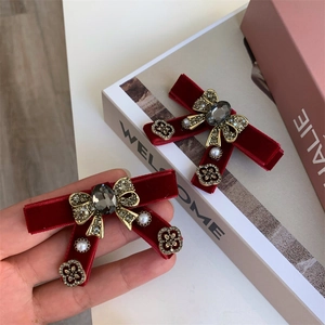 Detailed macro view of burgundy velvet bow hair clips with grey rhinestones and pearls