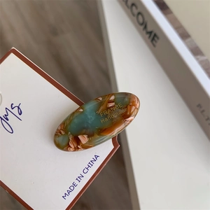Close-up of marble-patterned acetate hair clip with gold France Handmade lettering