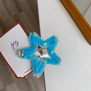 Dettaglio ravvicinato di un fermaglio per capelli blu a forma di stella pelosa con paillettes