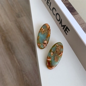 Detail of handmade acetate hair clip with blue marble texture and gold lettering