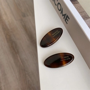 Detail of acetate tortoise shell hair clips featuring golden France Handmade lettering