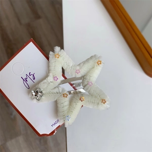 Dettaglio molletta a stella in peluche bianca con paillettes colorate e stella metallica