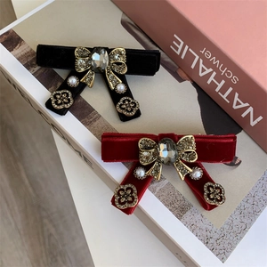Detail of luxury velvet bow hair clips with crystals and pearls in black and wine red
