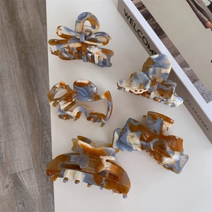Brown acetate hair claw clips with bow and marble pattern set on a minimalist desk