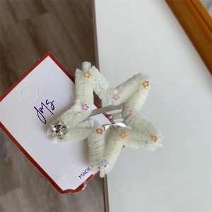 Dettaglio di un fermaglio per capelli a stella soffice con paillettes colorate e clip