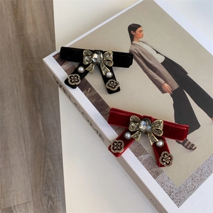 Detail showing velvet bow hair clips with central gemstones, pearls and gold flower charms