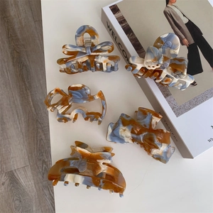 Maillard-style marble acetate hair claws set with bow and geometric designs on white table